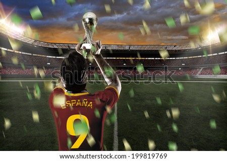 Spanish soccer player, celebrating the championship with a trophy in his hand. On a stadium.