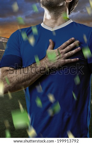 French soccer player, listening to the national anthem with his hand on his chest. On a stadium.