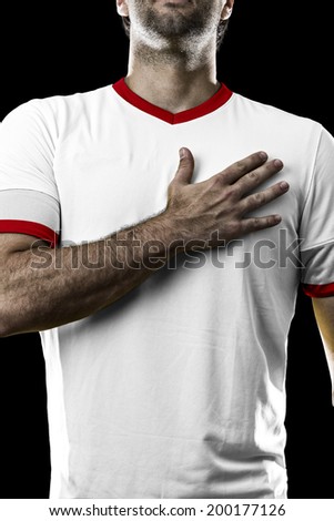 American soccer player, listening to the national anthem with his hand on his chest. On a black background.