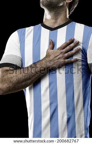 Argentinian soccer player, listening to the national anthem with his hand on his chest. On a black background.
