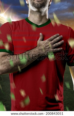 Portuguese soccer player, listening to the national anthem with his hand on his chest. On a stadium.