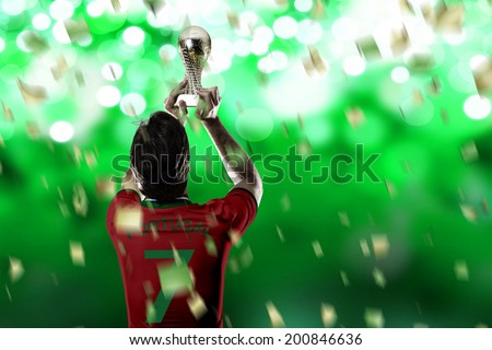 Portuguese soccer player, celebrating the championship with a trophy in his hand. On a green lights background.
