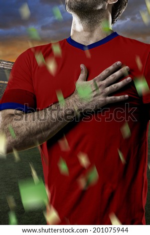Chilean soccer player, listening to the national anthem with his hand on his chest. On a stadium.