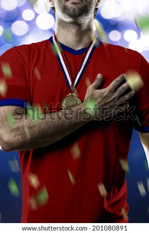 Chilean soccer player, listening to the national anthem with his hand on his chest. On a blue lights background.