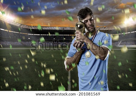 Uruguayan soccer player, celebrating the championship with a trophy in his hand. On a stadium.