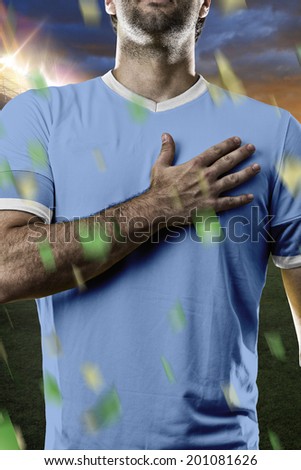 Uruguayan soccer player, listening to the national anthem with his hand on his chest. On a stadium.