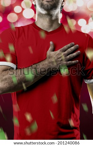 Swiss soccer player, listening to the national anthem with his hand on his chest. On a red lights background.