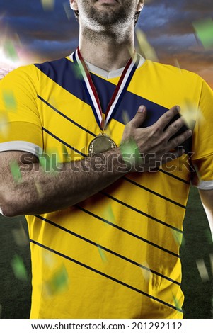Colombian soccer player, listening to the national anthem with his hand on his chest. On a stadium.