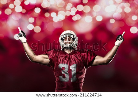 Football Player on a Red uniform celebrating on a red lights background.