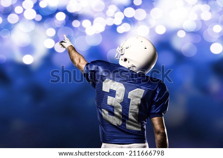 Football Player on a Blue uniform celebrating on a Blue lights background.