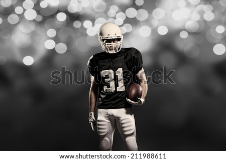 Football Player on a black uniform, on a black lights background.