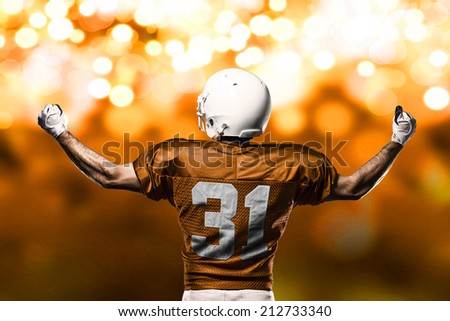 Football Player on a Orange uniform celebrating on a orange lights background.