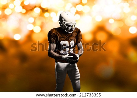 Football Player on a Orange uniform, on a orange lights background.