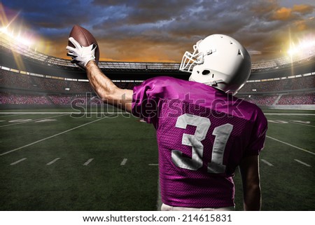 Football Player on a pink uniform celebrating on a stadium background.