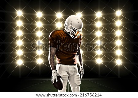 Football Player with a orange uniform celebrating in front of lights