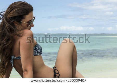 woman sitting on a stone, relaxing and watching a beautiful sea.