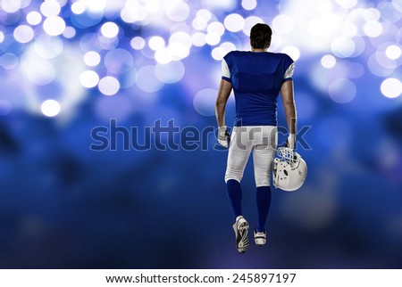 Football Player with a blue uniform walking, showing his back on a blue lights background.