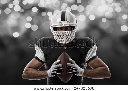 Football Player with a black uniform on a black lights background.