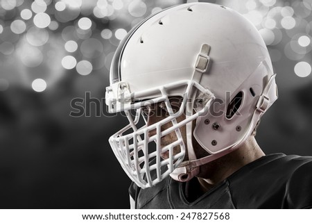 Close up of a Football Player with a black uniform on a black lights background.