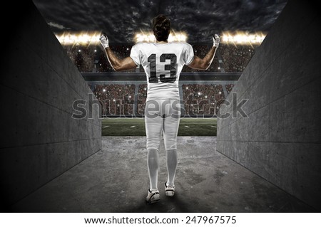 Football Player with a white uniform walking out of a Stadium tunnel.
