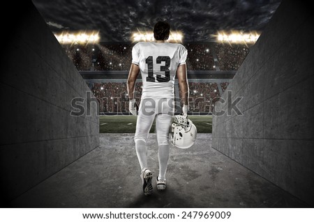 Football Player with a white uniform walking out of a Stadium tunnel.