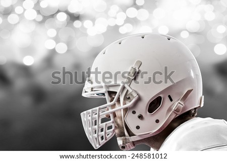 Close up of a Football Player with a white uniform on a white lights background.