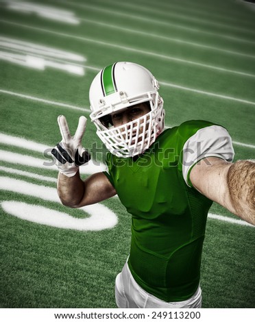 Football Player with a green uniform making a selfie on a football field.