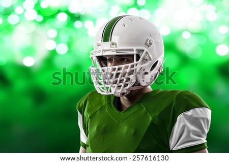 Close up of a Football Player with a green uniform on a green lights background.