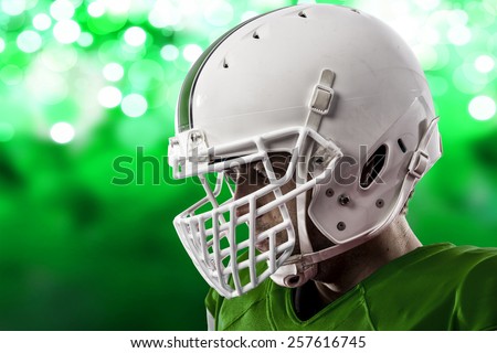 Close up of a Football Player with a green uniform on a green lights background.