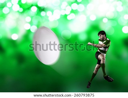 Rugby player in a green uniform kicking a ball on a green lights backgrond.