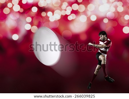 Rugby player in a red uniform kicking a ball on a red lights background.