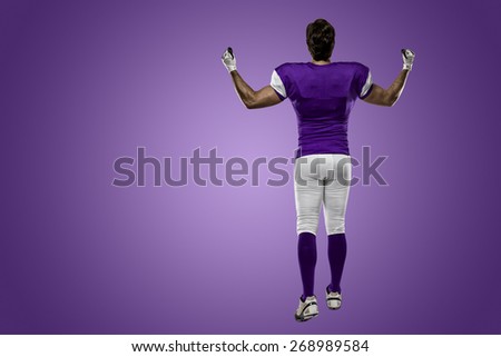 Football Player with a purple uniform walking, showing his back on a purple background.
