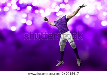 Football Player with a purple uniform making a catch on a purple lights background.