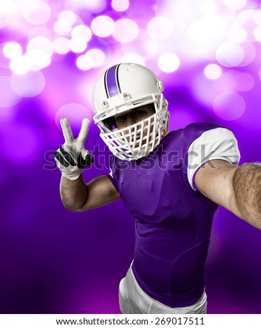 Football Player with a purple uniform making a selfie on a purple lights background.