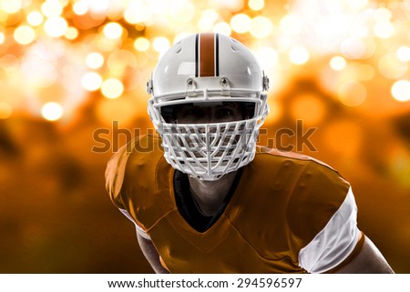 Close up of a Football Player with a orange uniform on a orange lights background.
