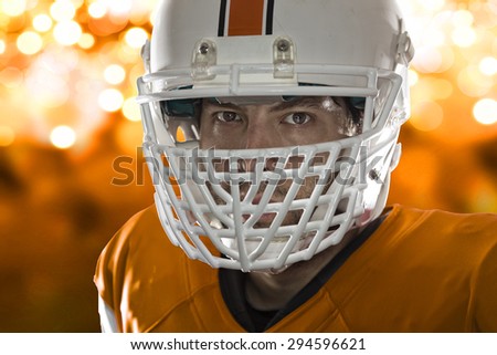Close up in the eyes of a Football Player with a orange uniform on a orange lights background.