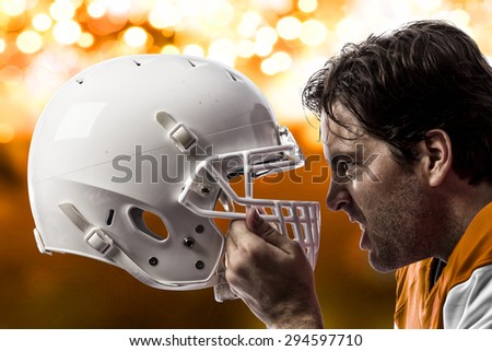Close up of a Football Player with a orange uniform on a orange lights background.
