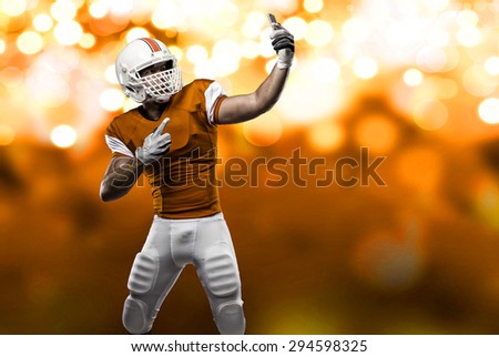 Football Player with a orange uniform making a selfie on a orange lights background.