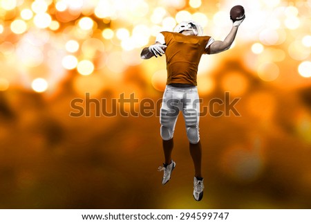 Football Player with a orange uniform making a catch on a orange lights background.