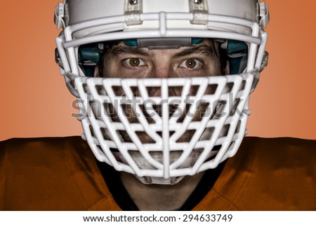 Close up in the eyes of a Football Player with a orange uniform on a orange background.