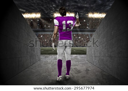 Football Player with a pink uniform walking out of a Stadium tunnel.