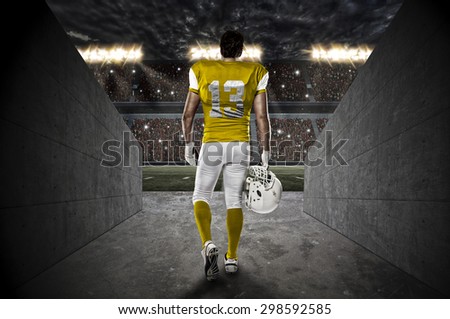 Football Player with a yellow uniform walking out of a Stadium tunnel.