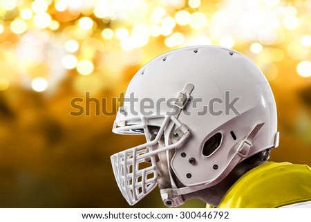 Close up of a Football Player with a yellow uniform on a yellow lights background.