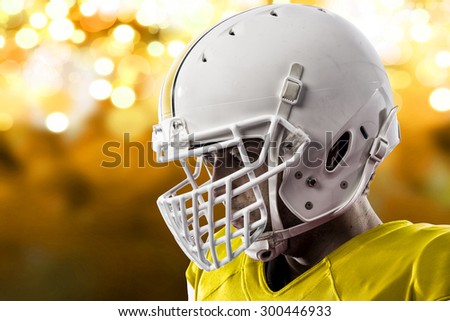 Close up of a Football Player with a yellow uniform on a yellow lights background.