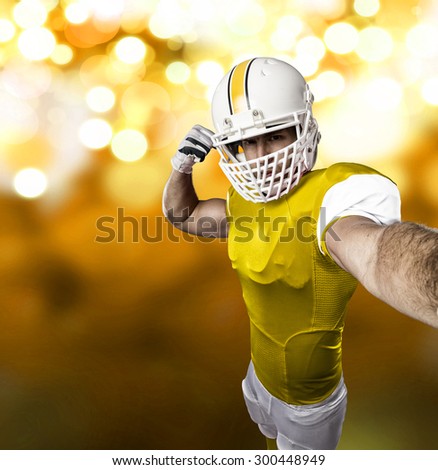 Football Player with a yellow uniform making a selfie on a yellow lights background.