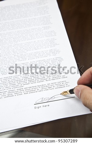 signing a contract. Focus is on the signature and the end of the pen.