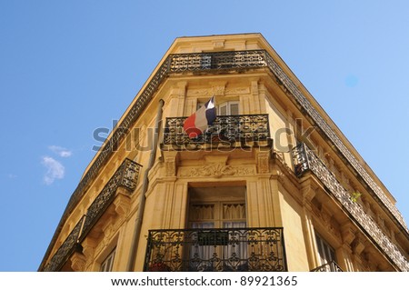 French architecture, building with french flag on the balcony.
