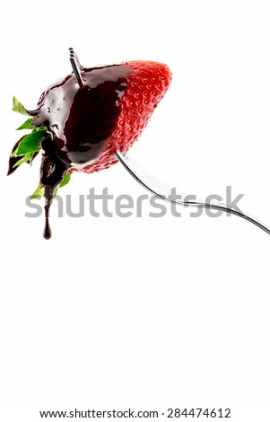Strawberry on fork with  liquid chocolate on a white background.Vertical image