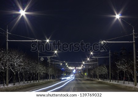 Fabulous night winter landscape, snow-covered road, traces bus and car headlights