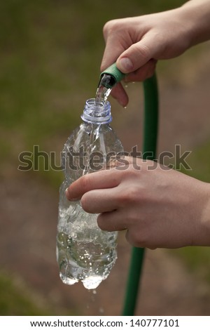 Filling a plastic bottle some water with a hose